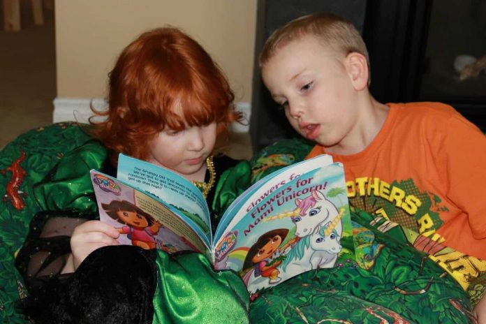 Our daughter Evey reading a Dora the Explorer book to her brother Gabe. Both children are homeschooled and Gabriel lives with autism.