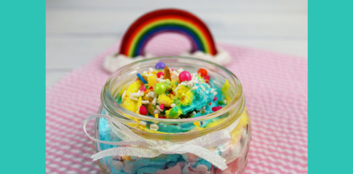 A glass jar containing unicorn whipped soap in blue, green, yellow, and pink