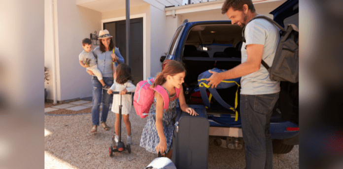 Family Road Trip Cover A family of two adults and two children are packing items into the back of a car for a road trip.