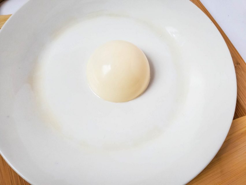 a half-sphere of white chocolate with the open side face down on a plate