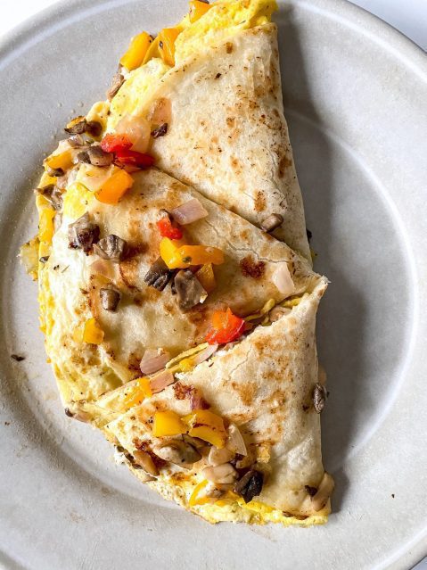 Vegetable breakfast quesadilla cut into three pieces on a white ceramic plate